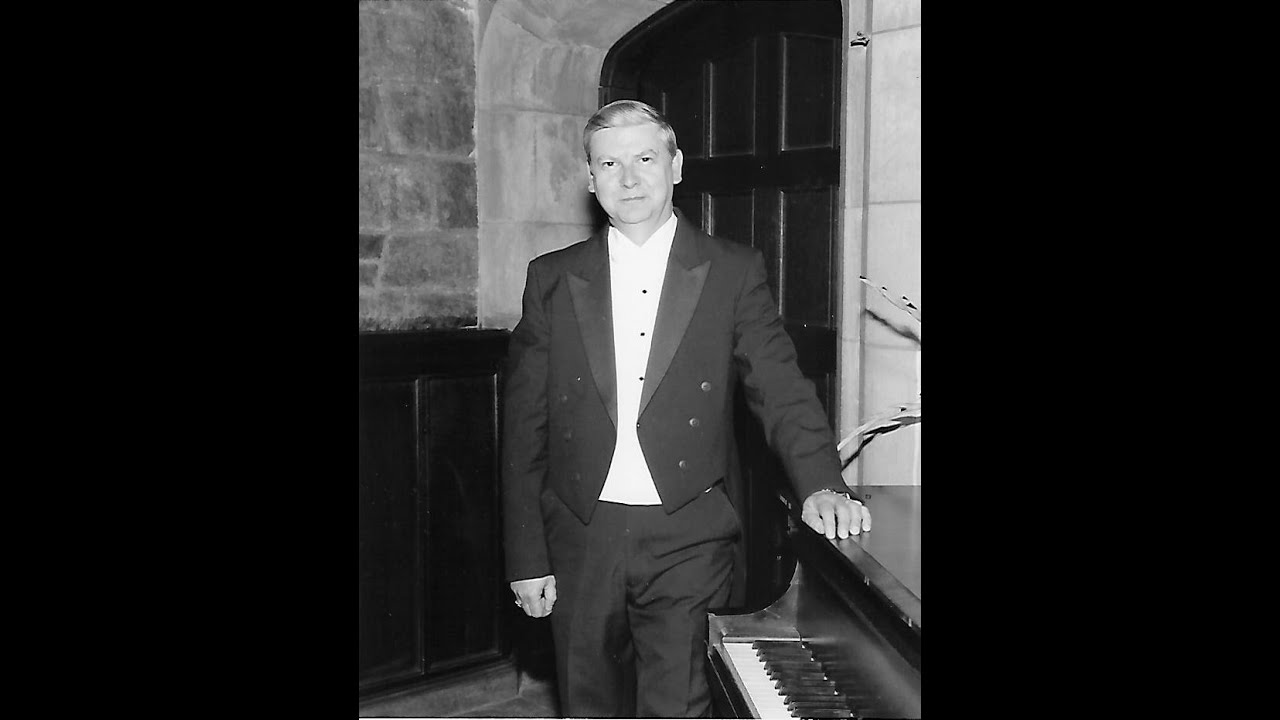 R. Wayne Walters in formal concert attire beside a piano